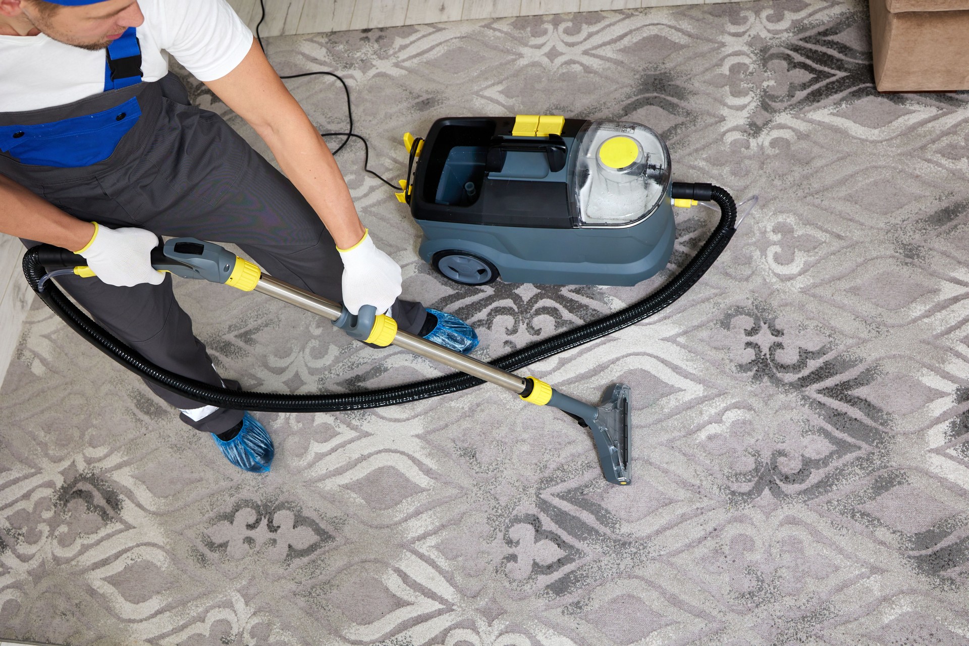 Specialized cleaning company worker with vacuum cleaner cleaning a carpet