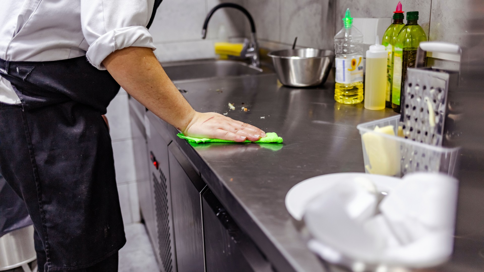 Cropped shot of a man cleaning a kitchen counter in commercial kitchen.